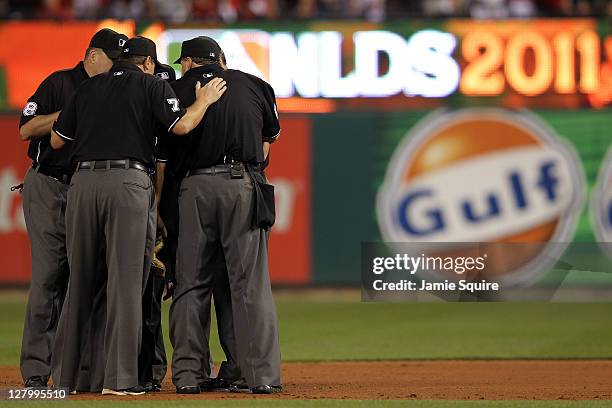 The umpire crew confers to overturn a call for an out on a catch by Skip Schumaker of the St. Louis Cardinals on a fly ball from Carlos Ruiz of the...