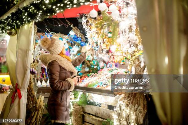 vrouw die zich voor de kraam van de straatmarkt van kerstmis bevindt - bazaar stockfoto's en -beelden