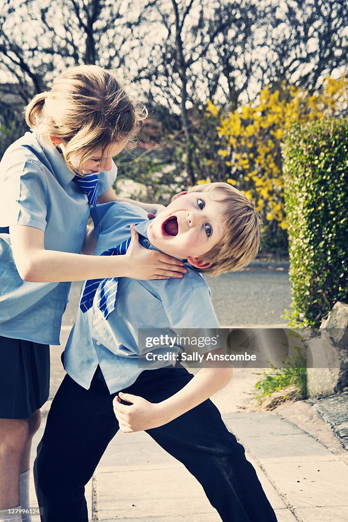 Two school children playing fighting outside