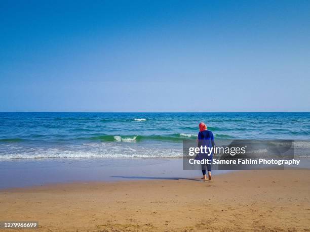 rear view of a muslim woman wearing a burkini on a beach - burkini bildbanksfoton och bilder