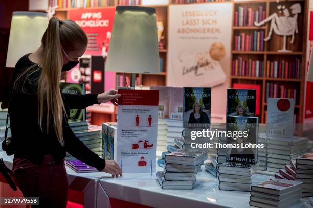 Woman places a sign with the distance rules between books before the opening conference of the 2020 Frankfurt Book Fair during the coronavirus...
