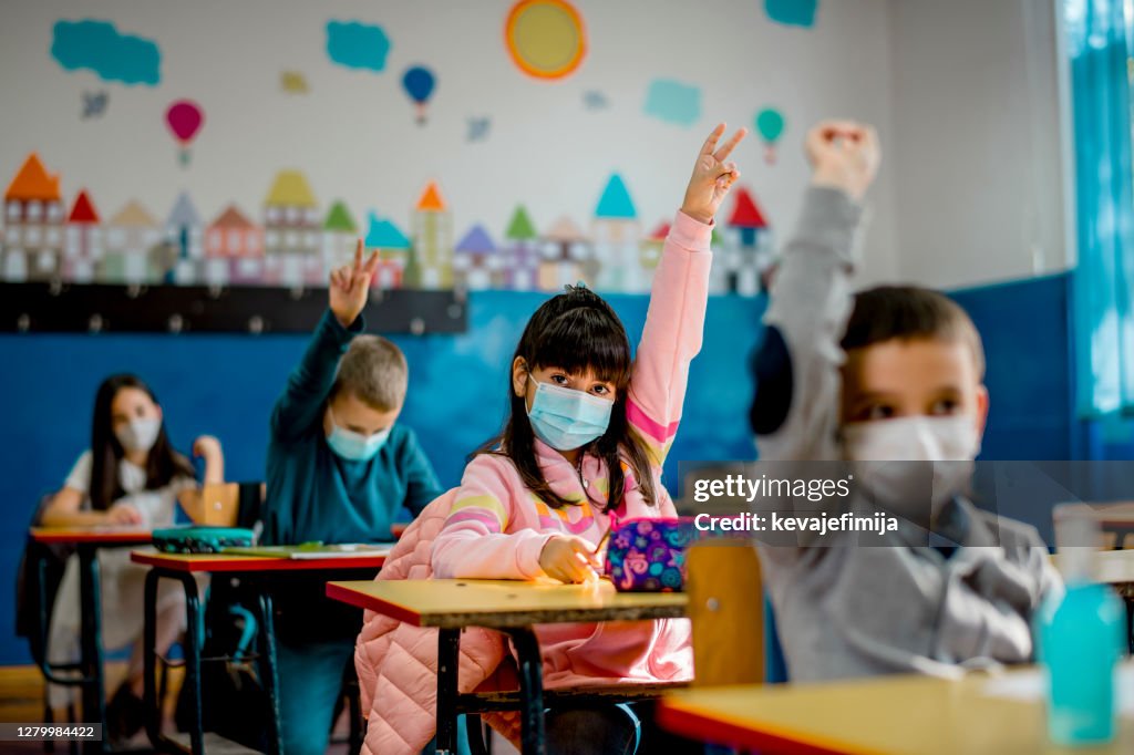 Basisschoolkinderen die een beschermende gezichtsmaskers in het klaslokaal dragen. Onderwijs tijdens epidemie.