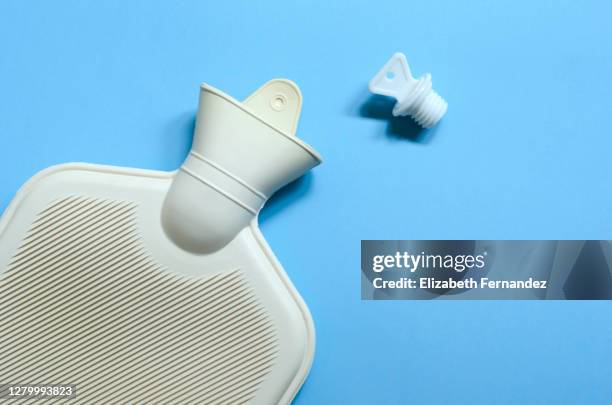 hot water bottle on blue background, top view - wärmflasche stock-fotos und bilder