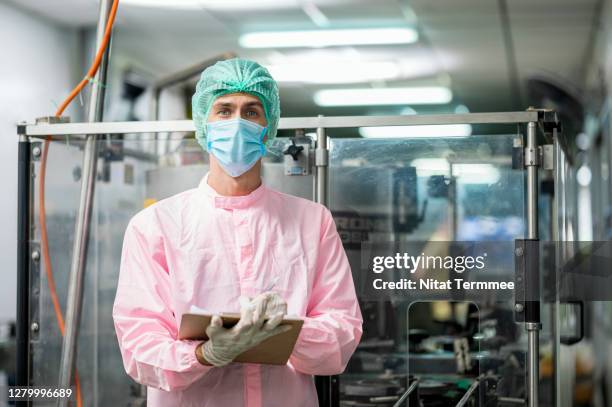 worker in clean suit coverall on a basil seed drink fruit flavors automated production line. food and beverage industry business. - hair net stock pictures, royalty-free photos & images