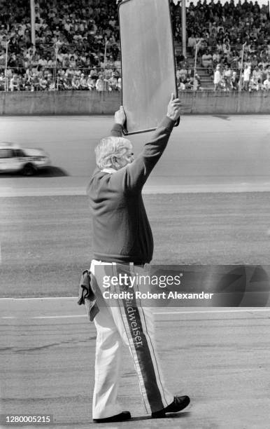 Car owner Junior Johnson holds up a sign showing his driver, Darrell Waltrip, his pit stall location during the running of the 1985 Daytona 500 stock...