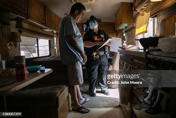 Maricopa County constable Darlene Martinez shows Hector Medrano court documents ordering his family's eviction from an RV park on October 07, 2020 in...