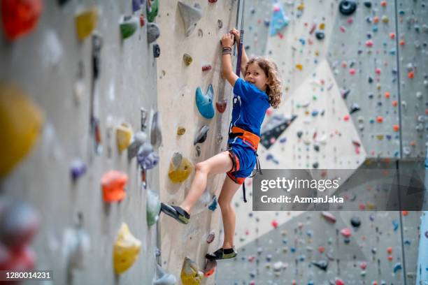 kind sportsman moving up verticale plak in klimmen centrum - klimmuur stockfoto's en -beelden