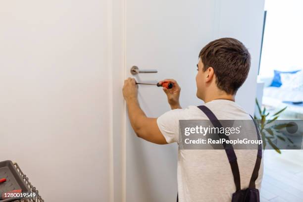 carpenter repairing door lock. installing a door handle. - locksmith stock pictures, royalty-free photos & images