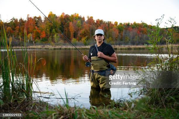 a teenaged fly-fisherman on a beautiful autumn day - boy river looking at camera stock pictures, royalty-free photos & images