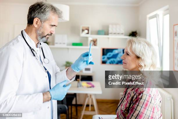doctor doing an eye exam on his senior patient - compassionate eye stock pictures, royalty-free photos & images
