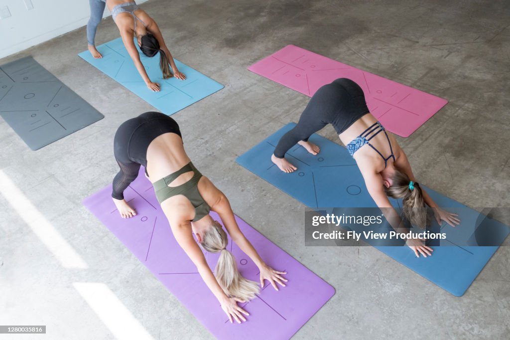 Women in yoga class doing downward dog pose