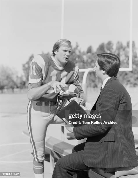 Los Angeles Rams quarterback Pat Haden talking to a man with a notebook on the training field, 1979.