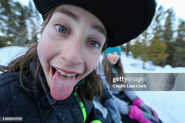 boy making funny face with sister in background out on a winter day - komiek stockfoto's en -beelden