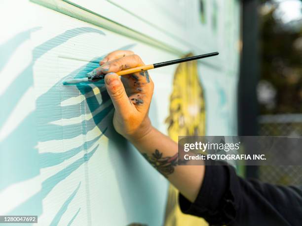 hand van vrouwelijke muurschilderingkunstenaar bij het werk - mural stockfoto's en -beelden