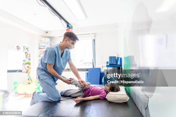 little girl during physical rehab with male therapist helping her stretch  her legs - injury prevention stock pictures, royalty-free photos & images