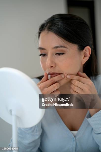 vrouw die op een puistje op haar gezicht plukt terwijl het worstelen met acne - pimple stockfoto's en -beelden