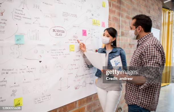 team sharing ideas at a creative office while wearing facemasks - business plan covid stock pictures, royalty-free photos & images