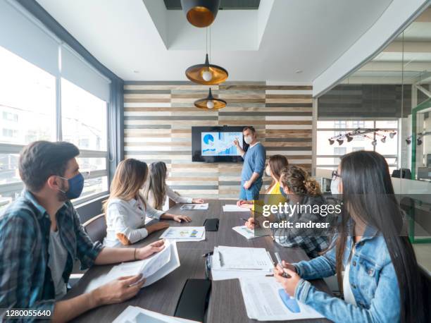 mensen sociaal distantiëren en het dragen van gezichtsmaskers in een bedrijfsvergadering bij het bureau - emergency planning stockfoto's en -beelden