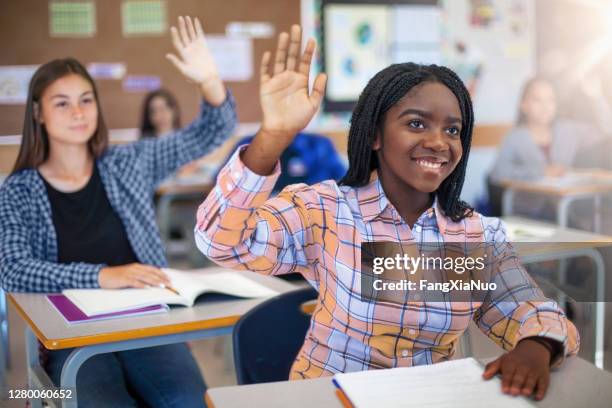 smiling diverse multi-cultural students raising hands in classroom - hand asking stock pictures, royalty-free photos & images