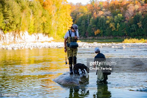 a teenaged fly-fishermen with their labrador puppy - waders imagens e fotografias de stock