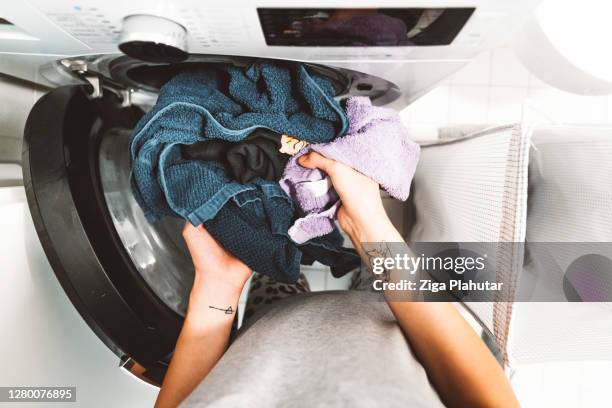 pov vrouwenhand die vuile was in de wasmachine zet - launderette stockfoto's en -beelden