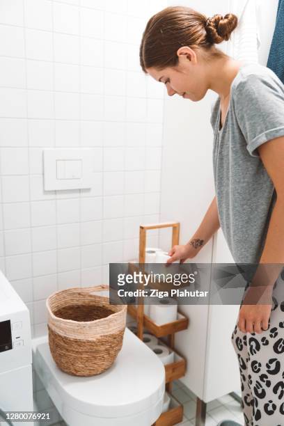 vertical photo - woman putting toilet paper on a stand next to the toilet - arrangement stock pictures, royalty-free photos & images