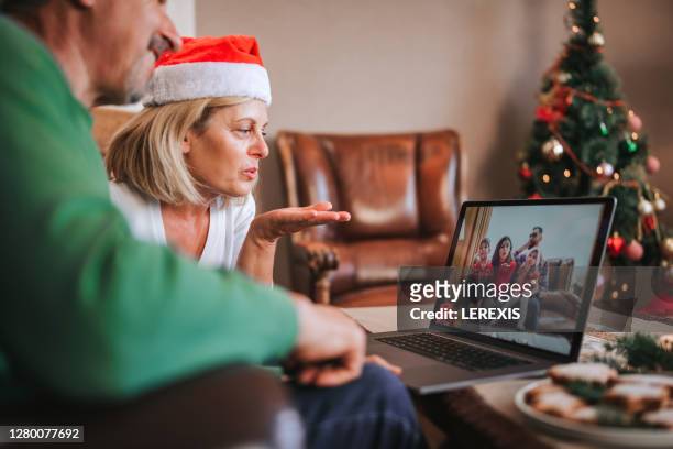 an elderly couple is having a video chat with their children who are away from them during the christmas holidays - virtual lunch stock pictures, royalty-free photos & images