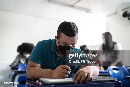 University / high school student with down syndrome wearing face mask while studying in the classroom University / high school student with down syndrome wearing face mask while studying in the classroom