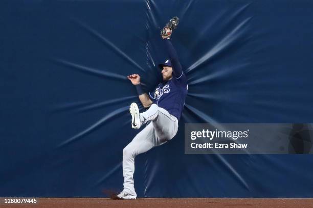 Kevin Kiermaier of the Tampa Bay Rays falls into the outfield wall to steal a home run from Alex Bregman of the Houston Astros during the first...