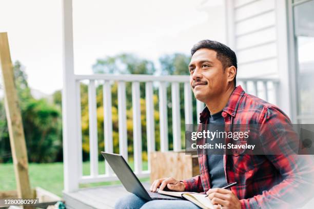 de zitting van de mens buiten die aan laptop werkt - polynesische etniciteit stockfoto's en -beelden
