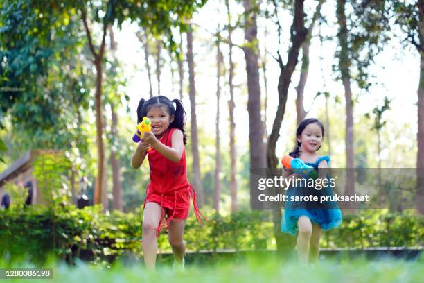 children playing with water gun squirt in the backyard. - toy gun stock pictures, royalty-free photos & images