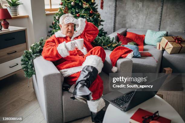 tired santa claus sitting in armchair and drinking coffee - man in costume stock pictures, royalty-free photos & images