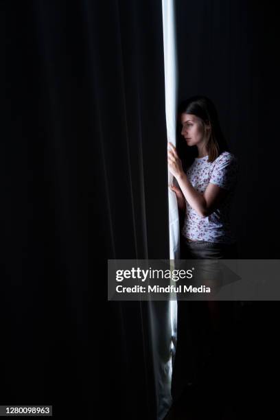 woman looking through window in dark room - peep window stock pictures, royalty-free photos & images