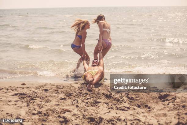 fun on the beach of the adriatic sea for three good friends - friend mischief stock pictures, royalty-free photos & images