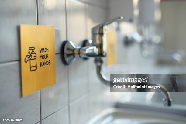 wash your hands sign on wall by water basin in public bathroom. - office bathroom stock-fotos und bilder