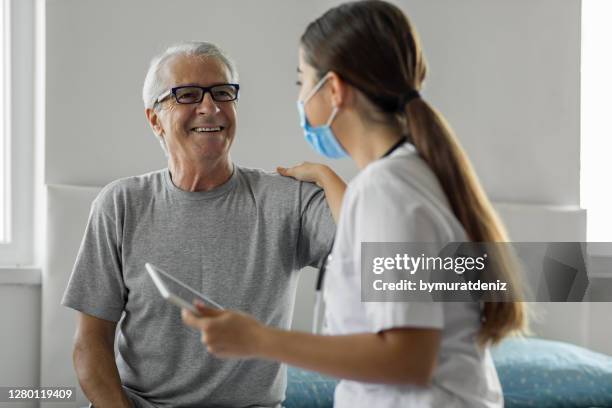 verticale du visiteur de santé et d’un homme aîné pendant la visite à la maison - infirmière et maison photos et images de collection