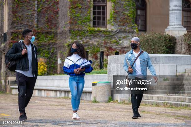 college friends walking together wearing protective face masks - small group of people stock pictures, royalty-free photos & images