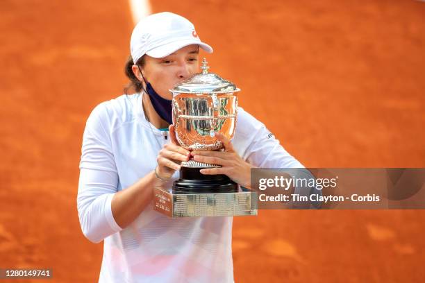 October 10. Iga Swiatek of Poland momentarily removes her mask to kiss the winners trophy after her victory against Sofia Kenin of the United States...