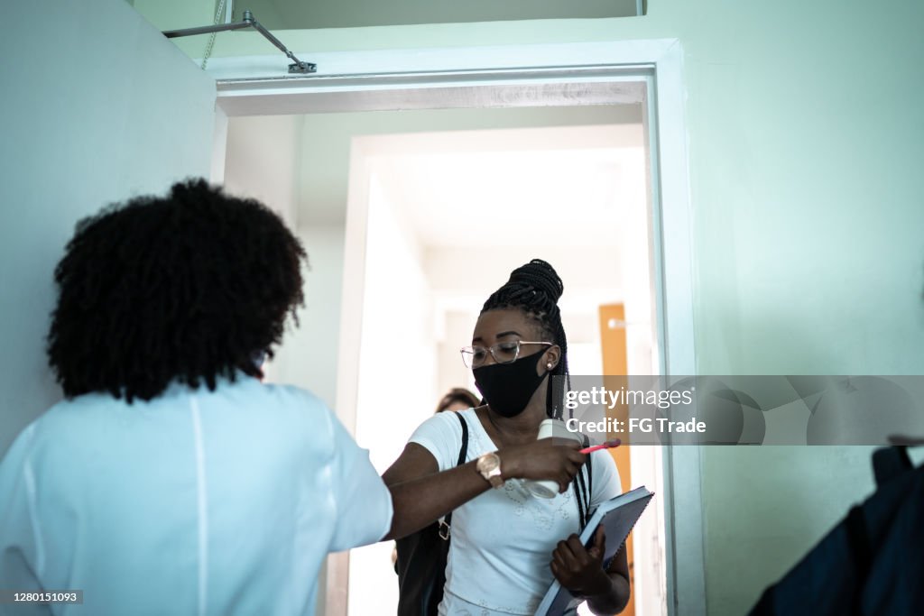 Students wearing face mask greeting teacher with elbow bumb