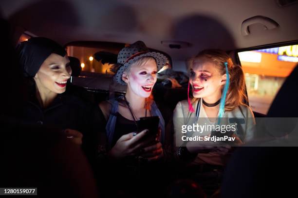 smiling female friends using their phones while driving to halloween party - period costume stock pictures, royalty-free photos & images
