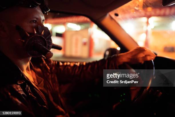 vista lateral de um jovem dirigindo para a festa de halloween - driving mask - fotografias e filmes do acervo