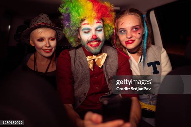 friends in costumes, driving in the car on halloween night while a young man is using his phone - period costume stock pictures, royalty-free photos & images