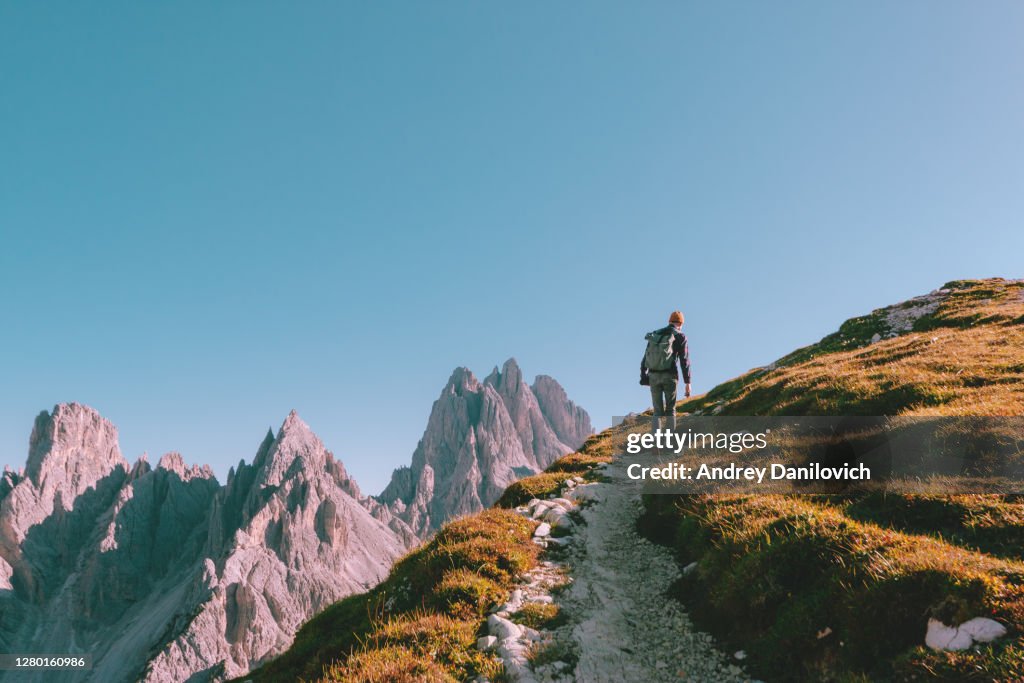 Mann wandert allein am Felsrand und blickt zum Horizont. Italienische Alpen in der Nähe des Tre Cime di Lavaredo.