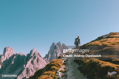 Man hiking alone on the edge of the rock and looking towards the horizon. Italian alps near the Tre Cime di Lavaredo. Man hiking alone on the edge of the rock and looking towards the horizon. Italian alps near the Tre Cime di Lavaredo.