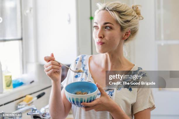 young woman eating a bowl of cereal - frühstücksflocken stock-fotos und bilder