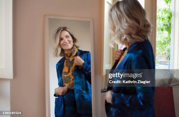 beautiful mature woman checking herself in the mirror - specchio foto e immagini stock