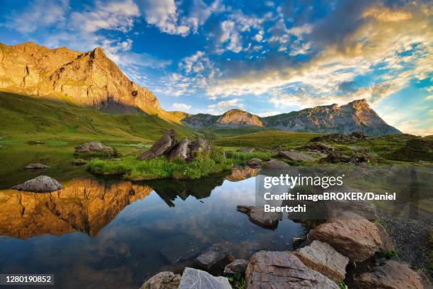 reflection of the mountains and clouds in the blausee at sunrise, melchsee-frutt, canton obwalden, switzerland - blausee stock-fotos und bilder