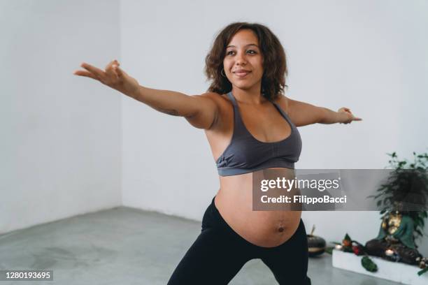 young woman practicing yoga during her pregnancy - prenatal yoga stock pictures, royalty-free photos & images