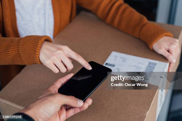 young woman receiving and signing for delivery - express delivery stock pictures, royalty-free photos & images