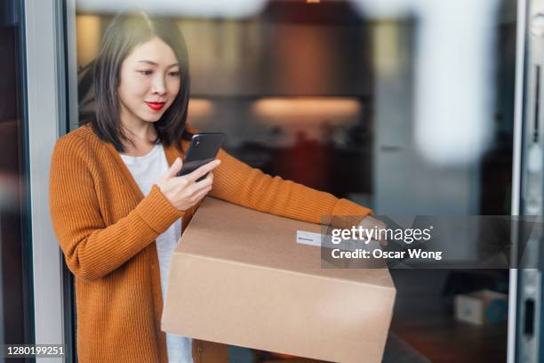 young woman tracking home delivery on smart phone - receiving package stock pictures, royalty-free photos & images